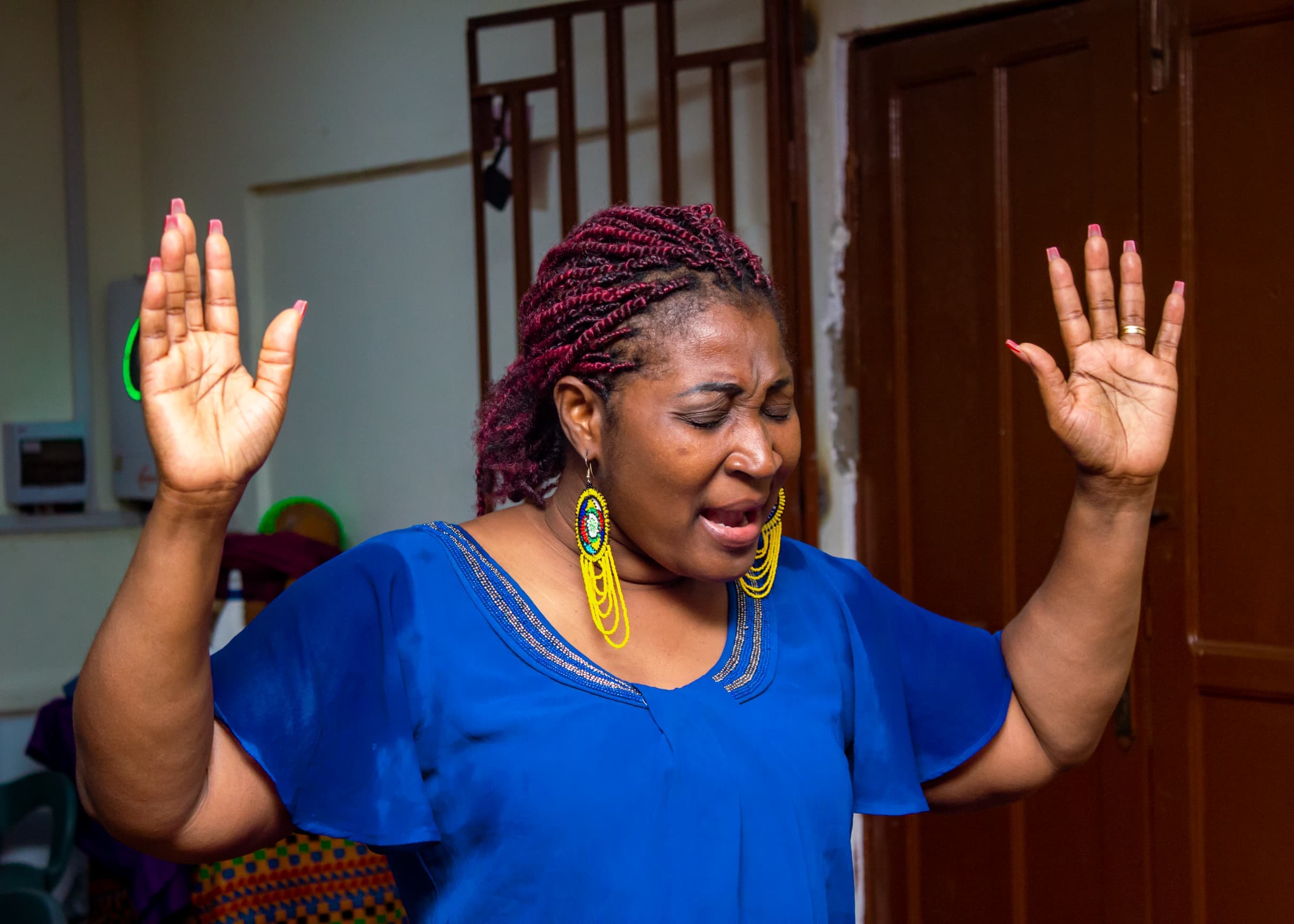 Woman in blue worshipping passionately during a service